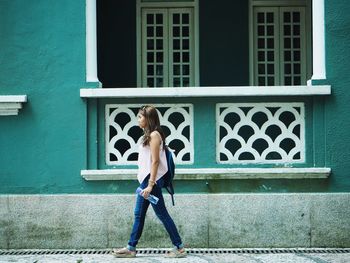 Full length rear view of woman standing against building