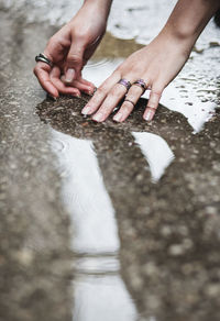 Woman's hands with rings in puddle