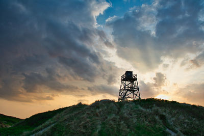 Low angle view of silhouette tower on field against sky