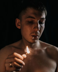 Close-up portrait of shirtless man against black background