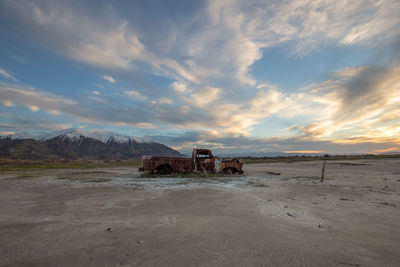 Abandoned truck on desert against sky