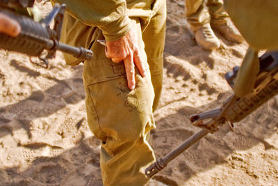 Midsection of man in uniform touching knee at beach