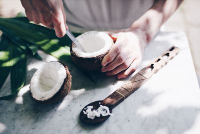 Midsection of man removing coconut on table