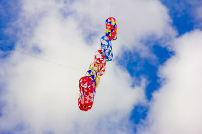 Low angle view of multi colored hanging kites against sky