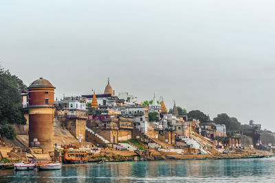 Buildings by sea against clear sky