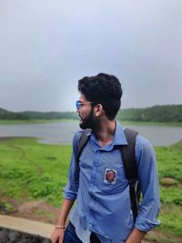 Young man standing on land against sky