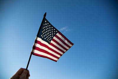 Low angle view of american flag against blue sky