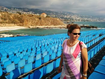 Mid adult woman walking amidst bleachers against sea