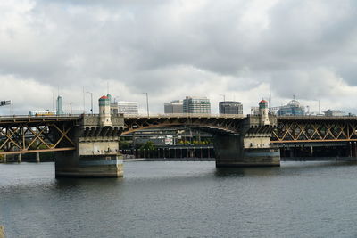 Bridge over river against sky in city