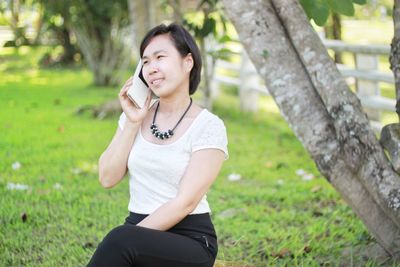 Young woman using mobile phone while sitting outdoors