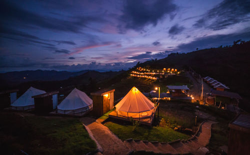 Tent on illuminated field against sky at sunset