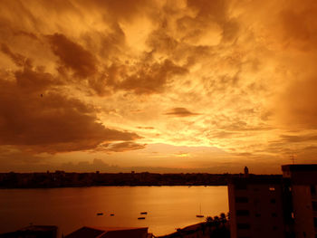 Scenic view of silhouette city against orange sky