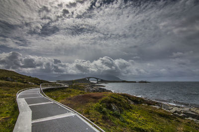 Scenic view of road by sea against sky