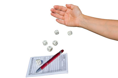 Close-up of hand holding paper against white background