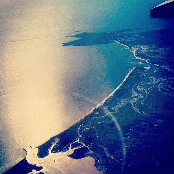 aerial view, sea, blue, scenics, water, high angle view, beauty in nature, nature, tranquility, tranquil scene, landscape, transportation, airplane, aircraft wing, day, coastline, outdoors, no people, mountain, idyllic