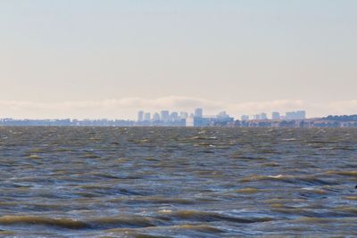 Sea by buildings against sky in city