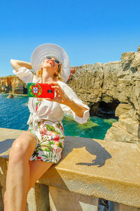 Woman taking selfie through mobile phone at beach