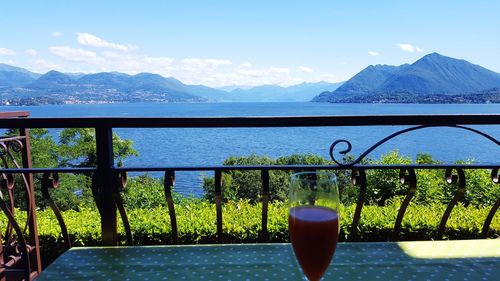 Close-up of beer on table by lake against mountains