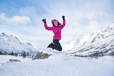 Woman with pink umbrella on snowcapped mountain against sky