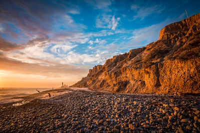 Beautiful beach sunset with sunlit bluffs and a rocky shore
