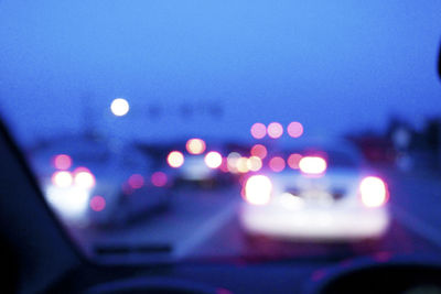 Defocused image of illuminated car on road at night