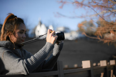 Young woman using mobile phone against sky