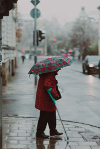 Rear view of woman with umbrella walking on street