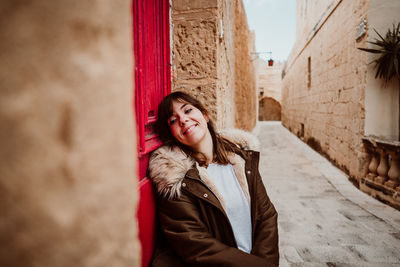 Full length of woman standing in alley amidst building