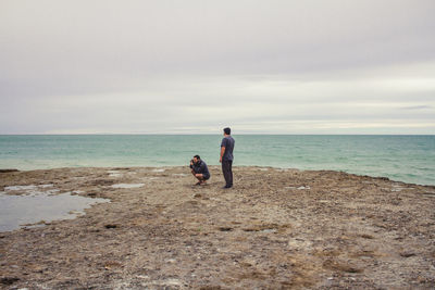 Boys standing on beach against sky