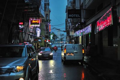 Cars on city street amidst buildings at night