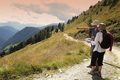 Couple hiker pointing at view while standing in the alps