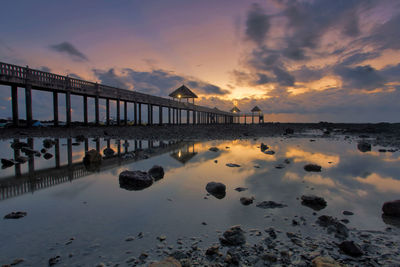 Pier over sea against sky during sunset