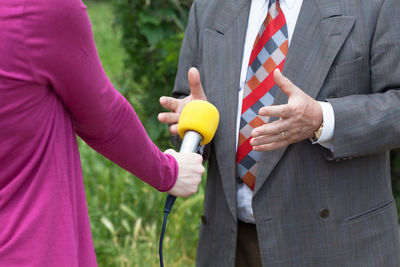 Midsection of female journalist with microphone taking interview of male politician
