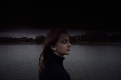 Side view of young woman looking away against lake