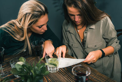 Young woman looking away while sitting on table