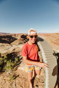 Female camper walks with sleeping pad setting up camp in the desert