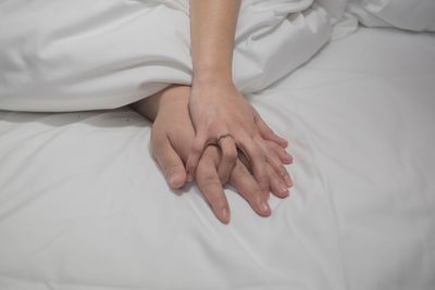 Close-up of couple hands on bed