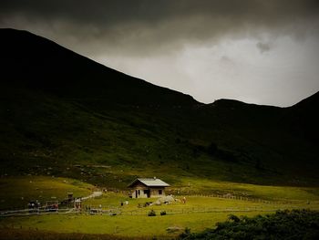 Houses on field by mountain against sky