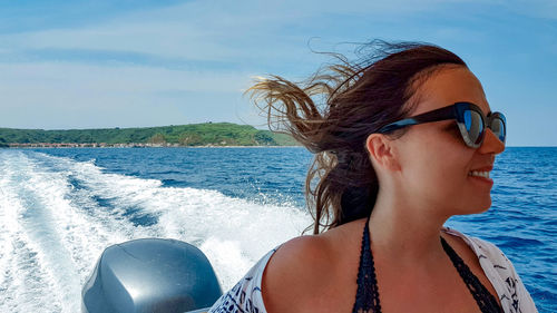 Young woman on boat at sea. wind in hair, lifestyle, summer vacation.