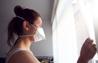 Portrait of beautiful woman holding window at home