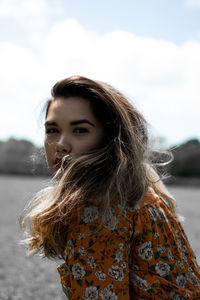 Portrait of a beautiful young woman against sky