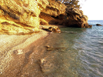 Rock formation on beach against sky