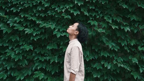Woman standing by ivy on tree