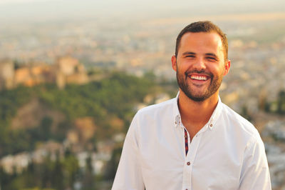 Portrait of happy young man against city