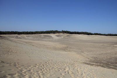 Scenic view of desert against clear blue sky