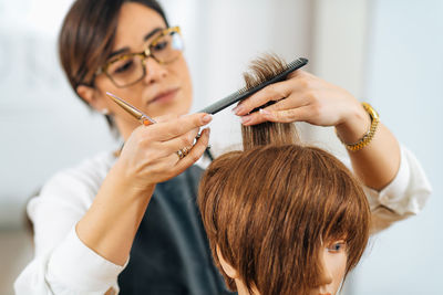 Hairdresser educator with students, explaining hair cutting technique on mannequin head for training