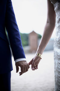 Midsection of couple holding hands outdoors