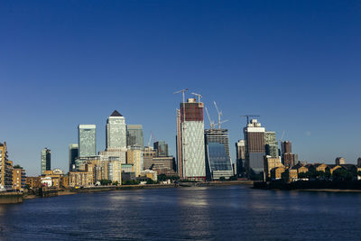 River by modern buildings against clear blue sky