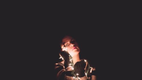 Close-up of young woman against black background