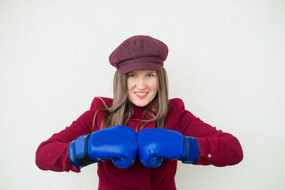 Portrait of smiling woman with boxing gloves against white background